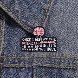 Broche en émail cerveau avec citation d'humour sur une veste en jean bleue