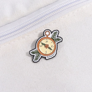 Close-up of vintage compass enamel brooch with floral details and Bible verse text