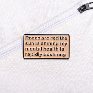 Enamel brooch with humorous quote on pink background pinned to a white canvas bag