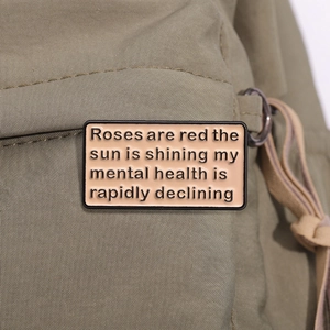 Enamel pin with roses are red text detail on olive green canvas fabric texture