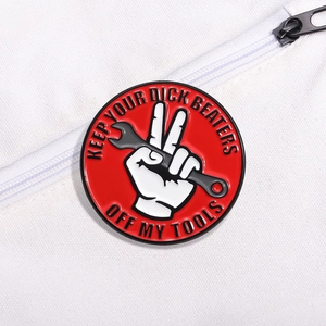Red enamel pin badge with Keep Your Dick Beaters Off My Tools slogan and wrench