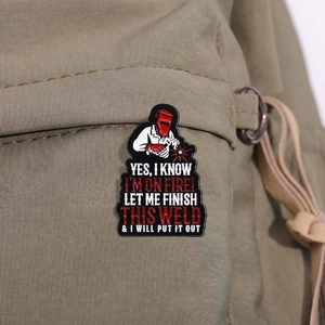 Detail of metal welding badge with funny text pinned on a green canvas backpack
