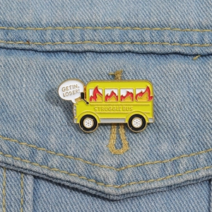 Close-up of yellow school bus enamel pin on denim jacket with Get In Loser text