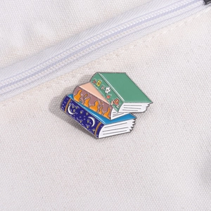 Creative stacked book enamel pin badge on canvas bag with floral and celestial motifs