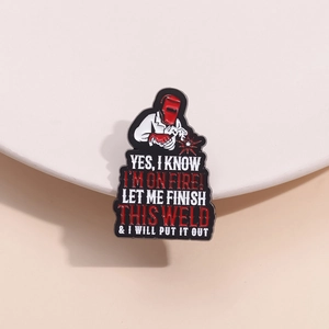 Macro shot of an enamel welding pin with a humorous character on a white ceramic surface