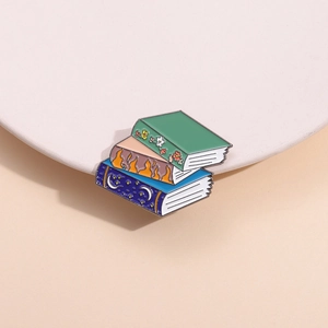 Detailed view of stacked fantasy book enamel pins with floral and celestial patterns
