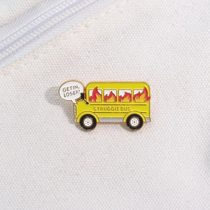 Detail of yellow school bus enamel pin with Struggle Bus and Get In Loser text on canvas