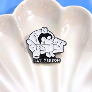 Detail shot of a monochrome Cat Person enamel pin on a white pearl shell display tray