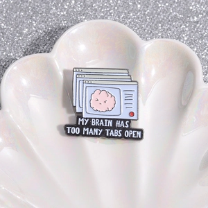 Macro shot of an enamel brain pin with My Brain Has Too Many Tabs Open text on shell