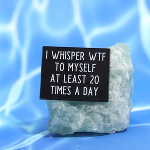 Detail view of rectangular enamel pin with quote on creative mineral stone background