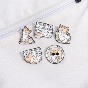 Set aus fünf orange-weißen Katzen-Emaille-Pins mit Slogans auf einer weißen Segeltuchtasche