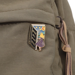 Detail of enameled book brooch with Starry Night design pinned on a green fabric bag