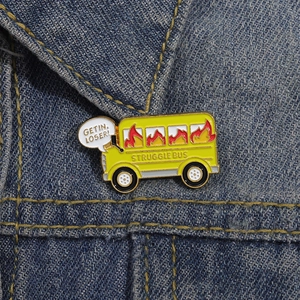 Funny yellow enamel struggle bus brooch with Get In Loser text on blue denim jacket