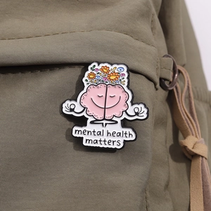 Close-up of Mental Health Matters enamel pin with pink brain and flowers on a canvas bag
