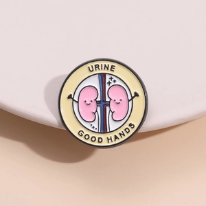 Dettaglio di una spilla smaltata a forma di rene con lo slogan medico URINE GOOD HANDS