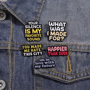 Detail of colorful enamel song lyric pins pinned onto a blue denim jacket collar