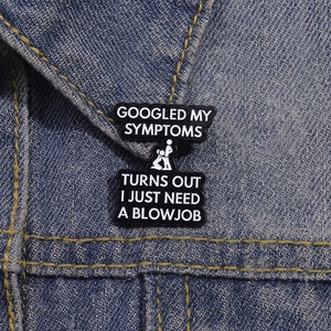 Detailed view of funny black enamel pin with cheeky text on blue denim jacket collar