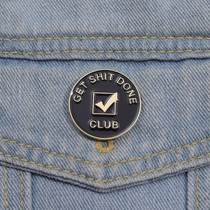 Get Shit Done Club enamel pin badge with gold metal trim on denim background