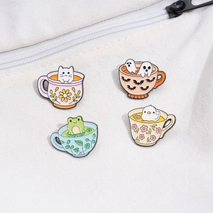 Detailed enamel pins featuring cartoon animals in teacups attached to a canvas bag