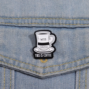 Gros plan d'une épingle en émail tasse à café sur veste en jean avec texte gravé