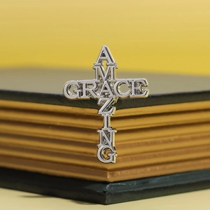 Broche en forme de croix Amazing Grace en argent sur fond de livre vintage chic