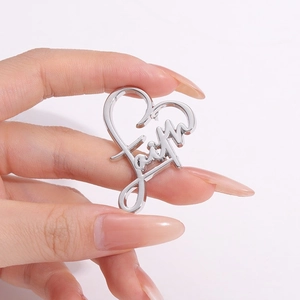 Pendentif coeur en métal argenté avec gravure faith tenu en main sur fond blanc