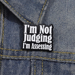 Broche en émail noir avec message humoristique fixée sur une veste en jean décontractée