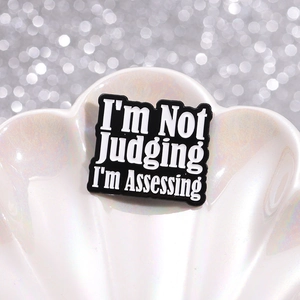 Macro d'épinglette en émail I'm Not Judging I'm Assessing sur un plateau en coquille