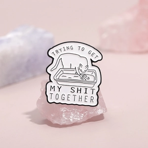 Broche en émail chat blanc nettoyant sa litière sur des pierres de cristal