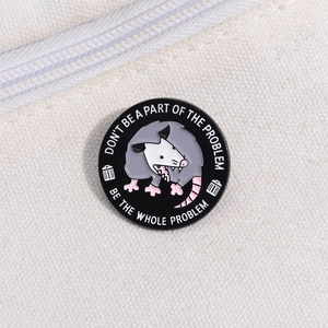 Detail of round enamel pin on canvas fabric featuring a funny cartoon opossum illustration