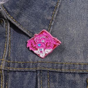 Pink enamel sabertooth tiger animal lapel pin badge on a blue denim jacket collar
