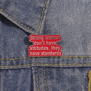 Enamel brooch with 'Strong women have standards' quote on a blue denim background