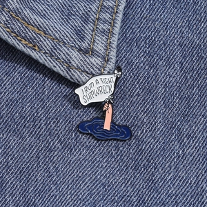 Detailed view of enamel shipwreck pin on blue denim fabric with creative flag design