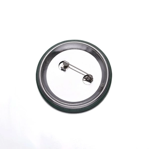 Macro shot of circular tinplate badge back showing metal pin fastener and smooth rolled edge