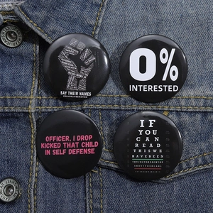 Set of four black tinplate badges with social slogans pinned on blue denim fabric jacket