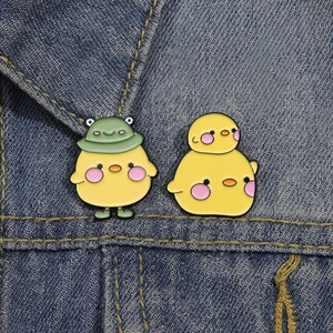 Broches en émail poussin jaune avec chapeau de grenouille sur veste en jean bleue