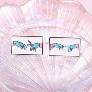 Detailaufnahme medizinischer Emaille-Pins mit OP-Handmotiven auf einem Prisma-Tablett