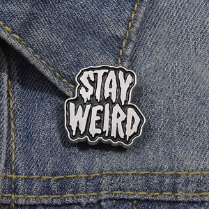 STAY WEIRD enamel pin on denim jacket with black and white drip oil alloy design