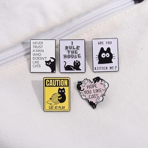 Détail d'un lot de cinq pin's chat en émail avec slogans drôles sur sac en toile blanche