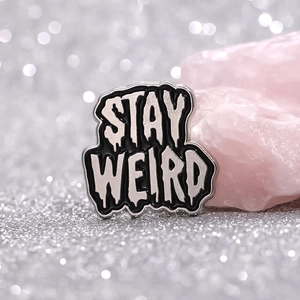Artistic STAY WEIRD enamel pin with melting font on sparkling silver sequin background