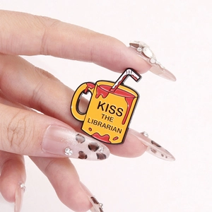 Creative yellow mug enamel pin featuring Kiss the Librarian text with straw and red details