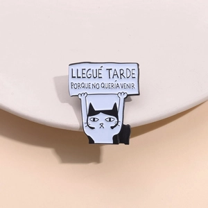 Spilla in smalto a forma di gatto bianco e nero con testo spagnolo su fondo beige