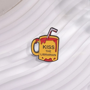 Detail of yellow enamel mug pin with Kiss the Librarian text and straw on white texture
