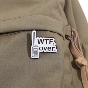Gros plan du pin's émaillé talkie-walkie vintage avec slogan WTF sur sac à dos