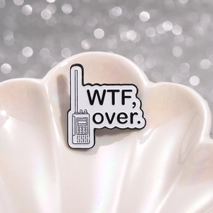 Épinglette de talkie-walkie avec texte 'WTF, over.' sur fond de coquillage blanc