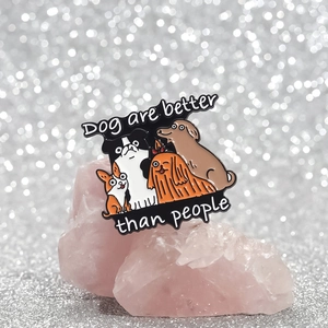 Detail of dog enamel pins with text Dogs are better than people on pink quartz stone