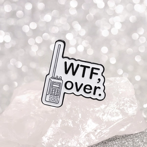 Détail macro du pin's émaillé talkie-walkie noir et blanc avec texte WTF sur des cristaux