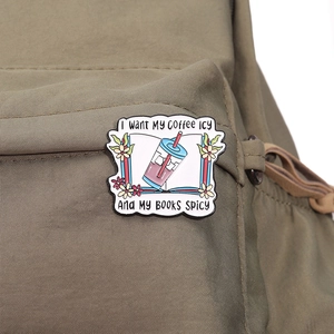 Pin's en émail café et livre avec des fleurs sur un sac en toile marron