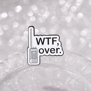 Gros plan d'un pin's talkie-walkie avec texte 'WTF, over.' sur fond brillant argenté