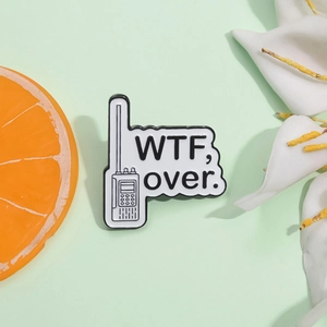 Détail du pin's émaillé en forme de talkie-walkie avec texte humoristique sur carte